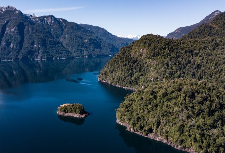 Vista aérea del Lago Chapo con un islote y montañas boscosas